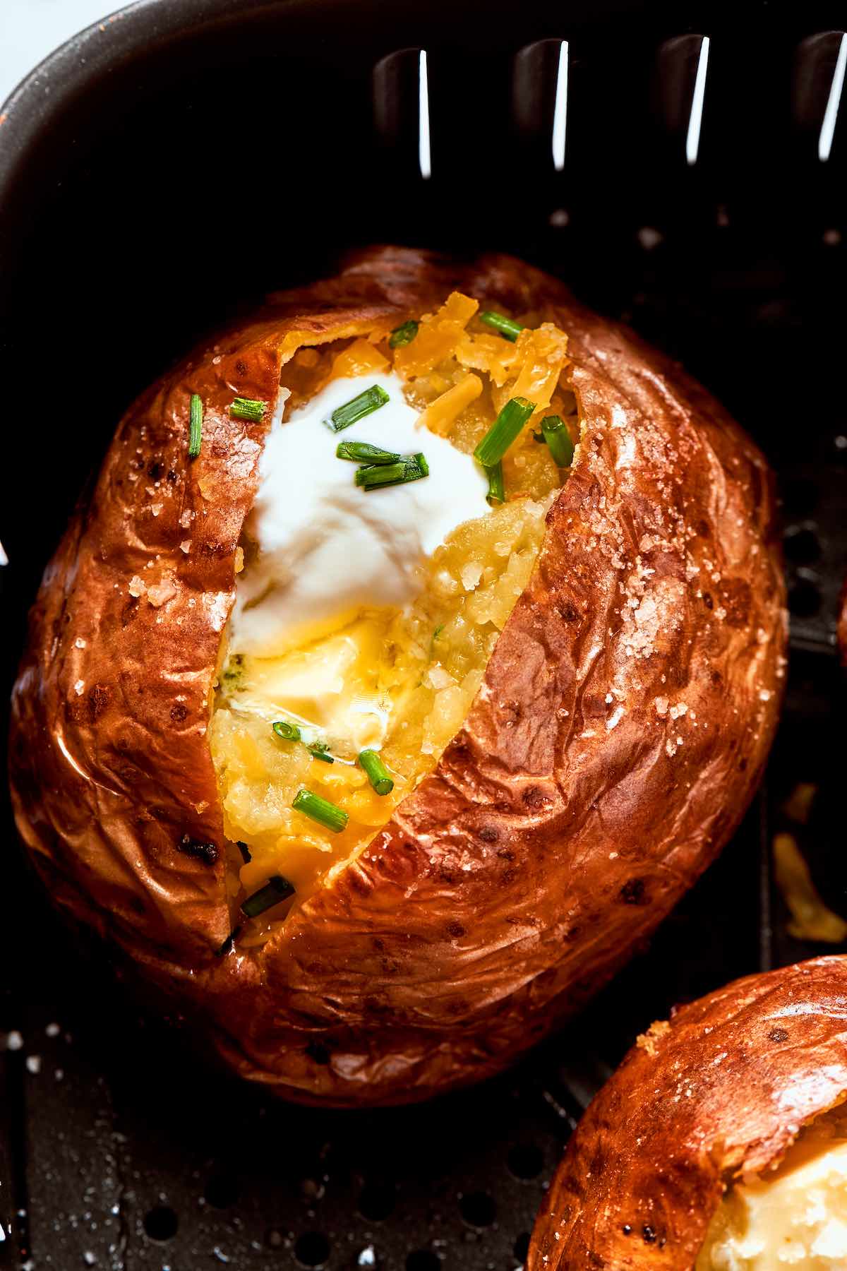 air fryer baked potato with sour cream and melted butter on top.